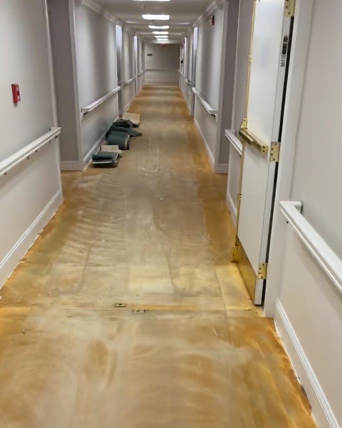 Before: the facility corridor at the fire doors with the old carpet torn out to the bare floor