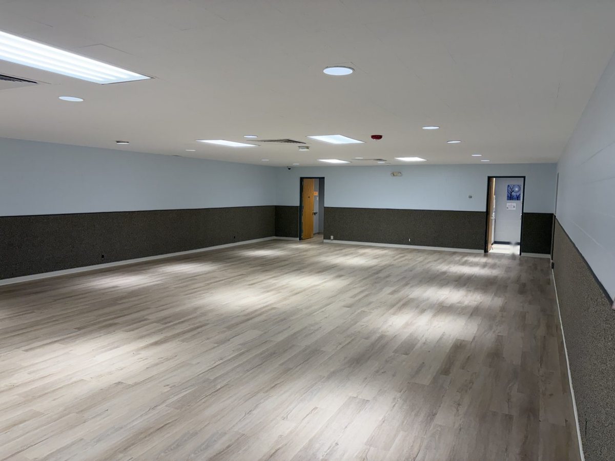 Large commercial room finished in light oak-look LVP, looking toward two doorways