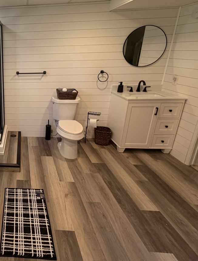 New wood-look LVP through a finished basement bath and laundry room