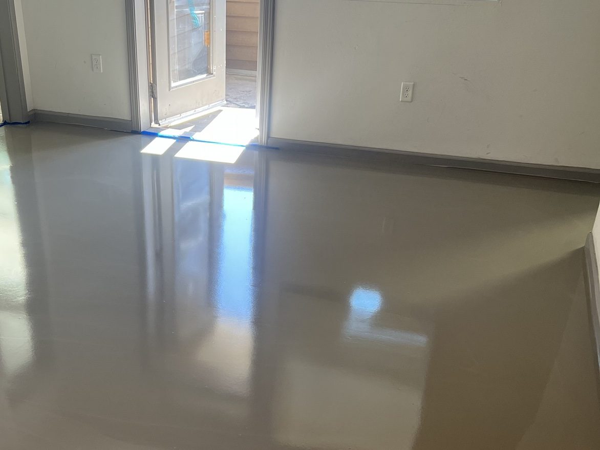 Fresh self-leveling underlayment poured glass-flat across an apartment floor